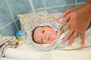 Drying of the child after a bath. bathing newborn. Cute newborn girl, a boy in a towel after a bath with his mother`s hands dryly