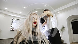 Drying long blonde hair with hair dryer and round brush.