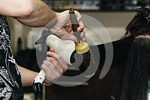 Drying long brown hair with hair dryer and round brush. Close-up