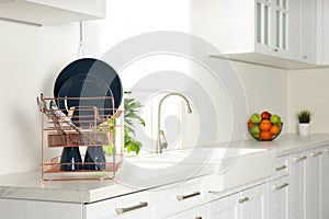 Drying rack with clean dishes on countertop in kitchen. Space for text