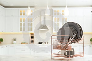 Drying rack with clean dishes on table in kitchen