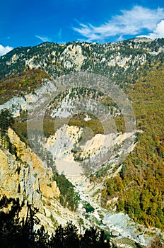 Drying up blue river flows deep in the canyon against the autumn forest.