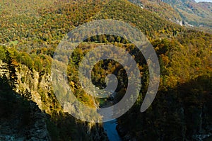 Drying up blue river flows deep in the canyon against the autumn forest.