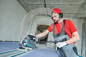 Drywall construction at home. Contractor worker milling gypsum plasterboard by hand-held router machine