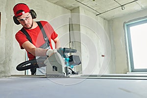 Drywall construction at home. Contractor worker milling gypsum plasterboard by hand-held router machine