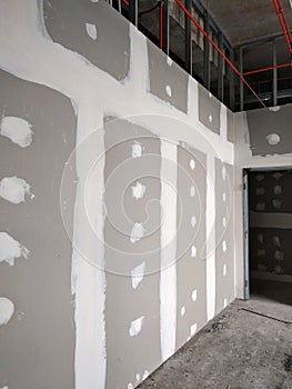 Drywall installation work in progress by construction workers at the construction site.