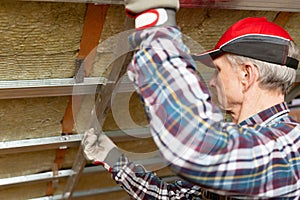 Drywall plaster wall metal fixation. Man holding metal ruler against metal frame on unfinished attic ceiling photo