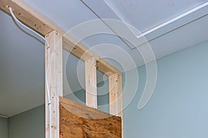 Drywall screwing plasterboard mounting to wooden beams at a wall