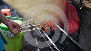 DSatay seller is grilling the satay by tradisional bamboo fan