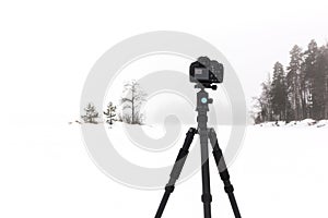 DSLR camera on a tripod outdoors in foggy landscape