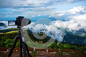 Dslr digital professional camera stand on tripod photographing mountain, Blue sky and cloud landscape.