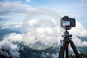 Dslr digital professional camera stand on tripod photographing mountain, Blue sky and cloud landscape.