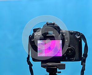 DSLR LCD display screen with Pixel texture of the camera matrix on a tripod on blue Background