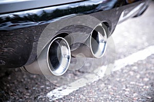 Dual exhaust pipes of a sports car. Silver color with soot from smoke. Close up