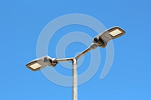 Dual modern LED street lights with adjustable angle mounted on single tall metal pole