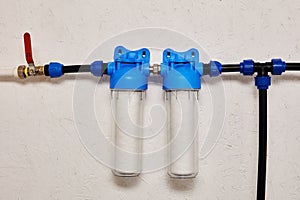 Dual Stage Water Filtration System Installed on a White Wal