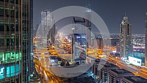 Dubai city skyline panoramic view with metro and cars moving on city's busiest highway aerial night timelapse