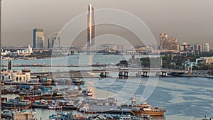 Dubai creek landscape with boats and ship in port and modern buildings in the background during sunset