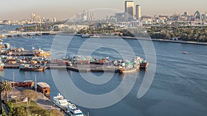 Dubai creek landscape timelapse with boats and ship in port and modern buildings in the background during sunset