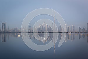 Dubai Downtown skyline panorama with reflections in Dubai Creek, cold colors, seen from Dubai Creek Harbour.