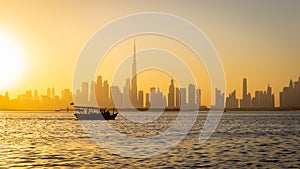 Dubai Downtown skyline panorama during sunset with a silhouette of a tourist boat.