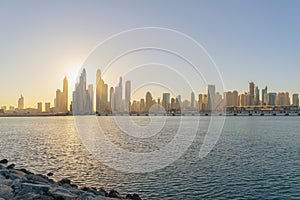 Dubai Downtown skyline with waves on sea beach, United Arab Emirates or UAE. Financial district in travel vacation concept. Urban