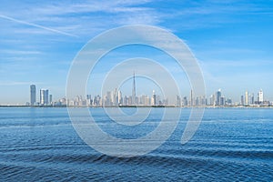 Dubai Downtown skyline with waves on sea beach, United Arab Emirates or UAE. Financial district in travel vacation concept. Urban