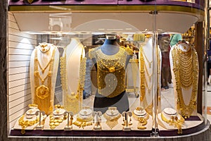 Dubai Gold Souk - golden jewelry - massive golden necklaces, armors, rings and hats displayed in a gold store