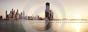 Dubai, January 13, 2023: Modern buildings with gold reflection of sunset on Dubai Marina bay view from Palm Jumeirah, UAE