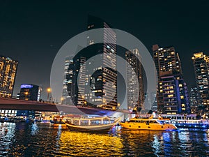 Dubai Marina, harbour, cruise boat and canal promenade view at night, in Dubai, United Arab Emirates