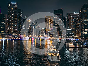 Dubai Marina, harbour, cruise boat and canal promenade view at night, in Dubai, United Arab Emirates