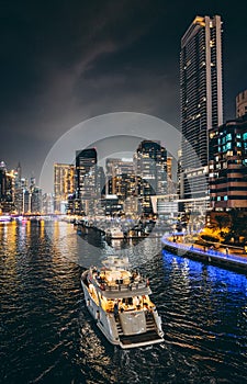 Dubai Marina, harbour, cruise boat and canal promenade view at night, in Dubai, United Arab Emirates