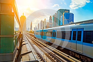 Dubai metro train on rails at background of skyscrapers. Famous outdoor subway Red Line.