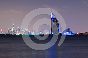 Dubai night landscape showing luxury skyline of modern hotels and skyscrapers. Illuminated Burj al Arab and Burj Khalifa.