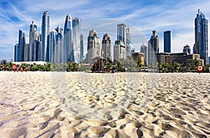 Dubai skyscraper skyline with palm trees and the sand of the beach