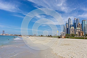 Dubai skyscraper skyline with palm trees and the sand of the beach with a rustic hut