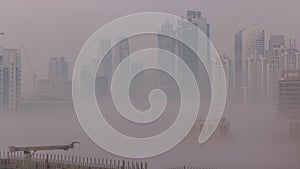 Dubai skyscrapers with morning fog in business bay district night to day timelapse.