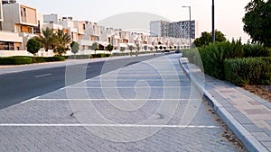 Dubai, UAE - 09.25.2022 - Slow motion footage of family riding their bikes near townhouses in Dubai South district. City