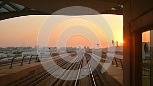 Dubai, UAE - 10th october, 2022: metro train on railway arrive to station in Dubai city with sunset orange sky background