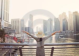 Dubai, UAE - 12th october, 2022: beautiful unrecognizable tourist woman in fashionable summer dress enjoy in Dubai marina in UAE