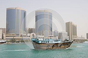 Dubai UAE A dhow old wooden sailing vessel cruises down Dubai Creek in front of the Rolex Tower.