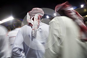 Dubai UAE small group of traditionally dressed Muslim men roaming grounds at Nad Al Sheba photo