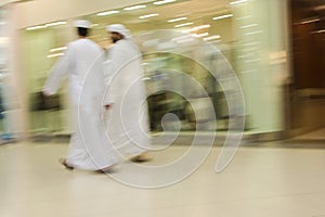 Dubai UAE Two men traditionally dressed in dishdashs and gutras white robes and headdresses.