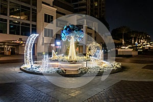 Night view to decorative small square with illuminated Muslim symbols at Dubai Marina in Dubai city, United Arab Emirates