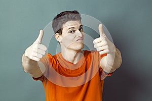 Dubious athletic man with orange t-shirt and thumbs up for success