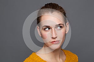 Dubious beautiful girl looking up, listening, observing emotions, studio shot