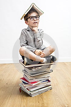 Dubious schoolboy with smart eyeglasses with book on his head
