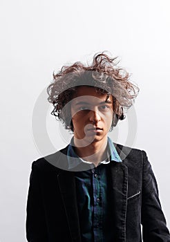 Dubious young man with awesome curly hairdo, with headphones, looking pensive, isolated on white backgrou