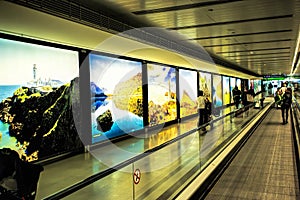 Dublin Airport people, passengers travelling with suitcases on walkway escalator in motion with highlighted images of Ireland in t