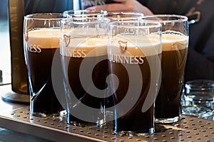 Pints of Guinness are being served in a pub in Dublin, Ireland